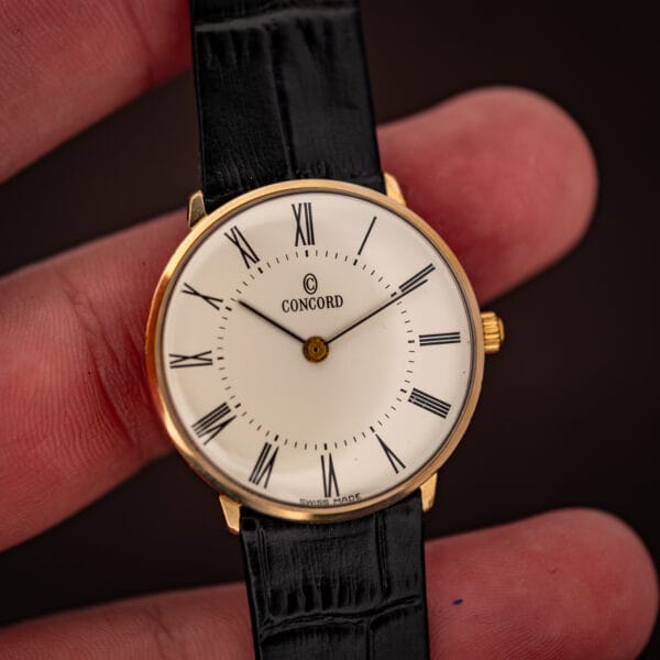 Vintage Concord dress watch held in hand, white Roman numeral dial reading SWISS MADE at six