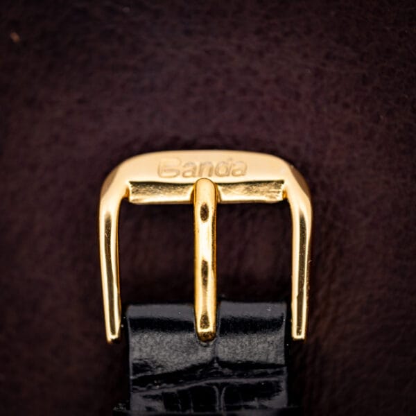 Concord watch gold-tone buckle on a black croc-pattern leather strap