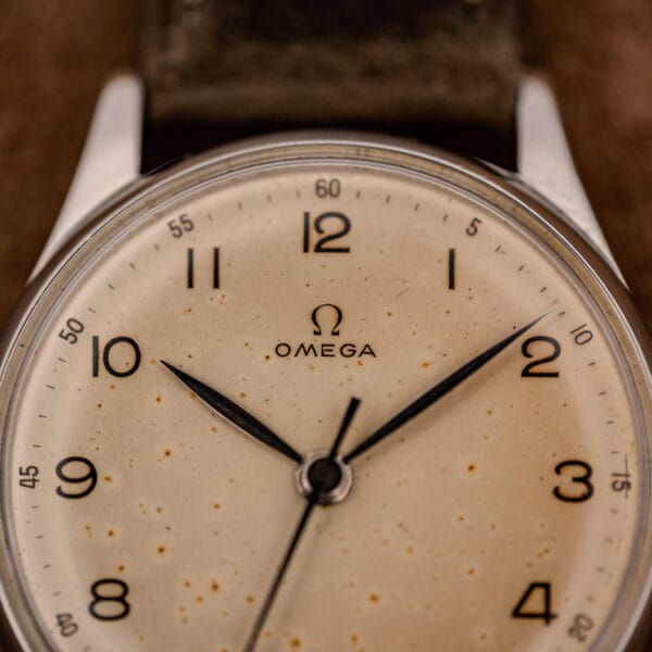 Macro of the Omega 2391 dial, OMEGA and Omega symbol at twelve with warm foxing across printed Arabic numerals
