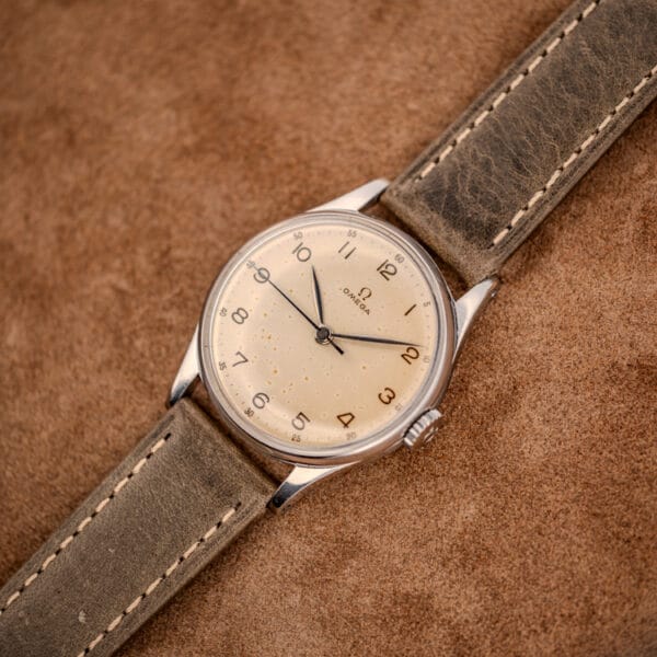 Vintage Omega 30T2 SC ref. 2391 angled on an olive strap, warm champagne dial and polished steel case