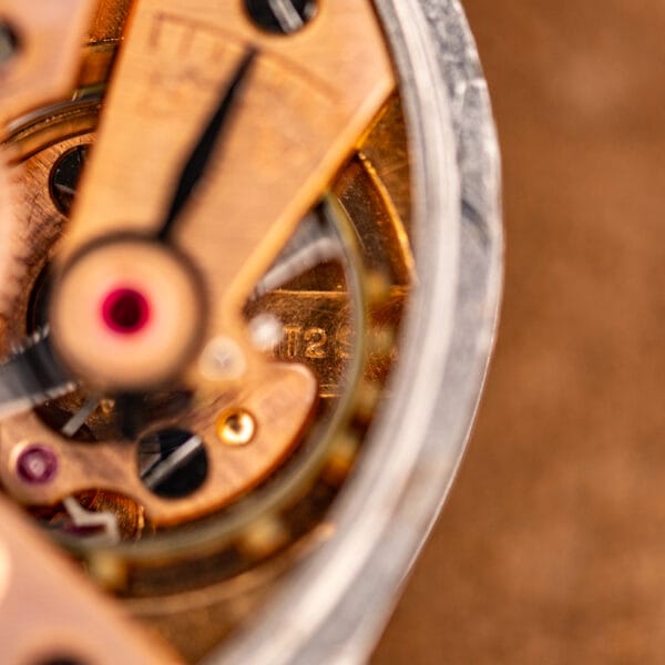 Macro of the Omega 30T2 SC bridge and jeweled center seconds pinion on the copper gilt movement