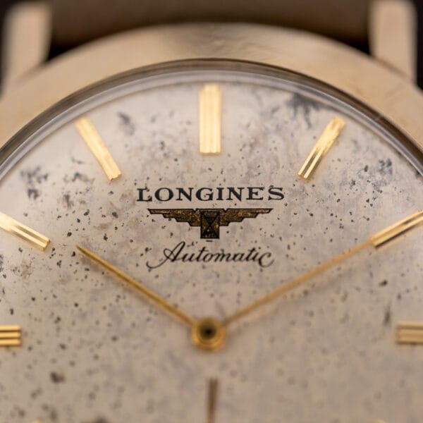 Longines 2264-1 dial macro showing the LONGINES winged hourglass logo, Automatic script, and grey speckled patina