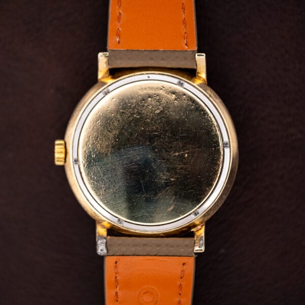 Longines 2264-1 outer gold filled caseback showing honest scratches and decades of wear, tan strap underside