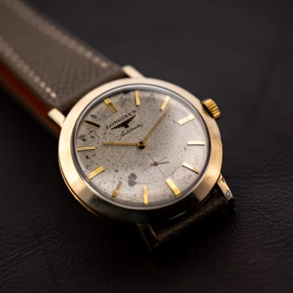 Vintage Longines 2264-1 automatic on a dark surface, gold filled case and speckled silver dial seen at an angle