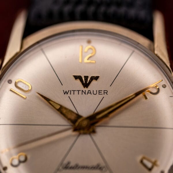 Wittnauer 2673-11SR dial close-up showing the W-shield logo, applied gold numerals, and dauphine hands with aged luminous channels