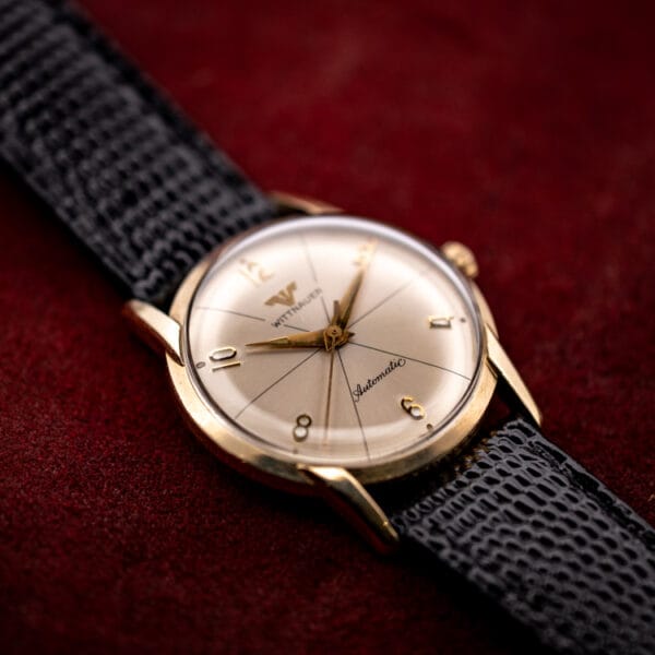 Vintage Wittnauer Automatic 2673-11SR gold filled dress watch angled on burgundy with a silvered starburst dial