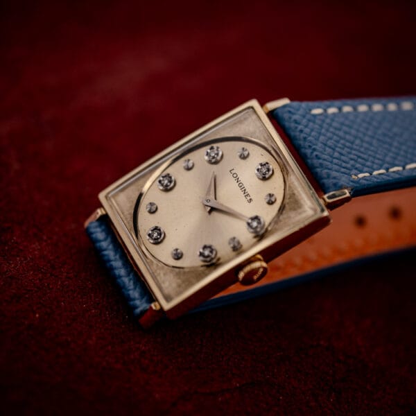 Longines Tank 3007-528 champagne diamond dial and signed crown in a three-quarter view on red velvet