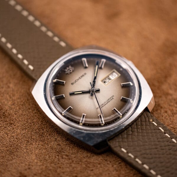 Bucherer automatic chronometer angled to show champagne center fading to smoky grey-brown at the dial edge