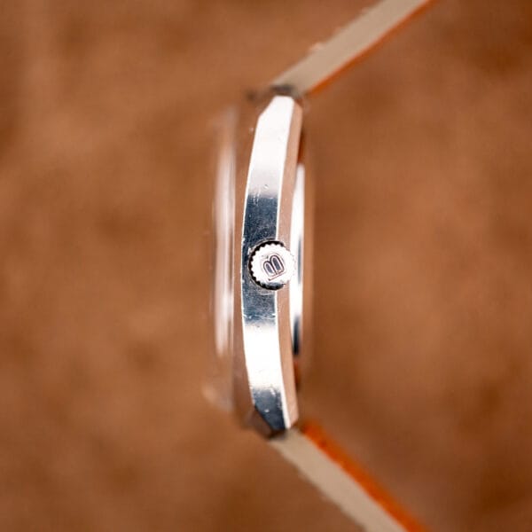 Signed crown bearing the Bucherer monogram on the polished stainless steel cushion case flank