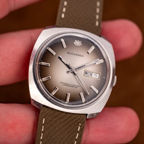 Bucherer cushion chronometer held in hand for scale, champagne ombre dial and MON 15 day-date aperture