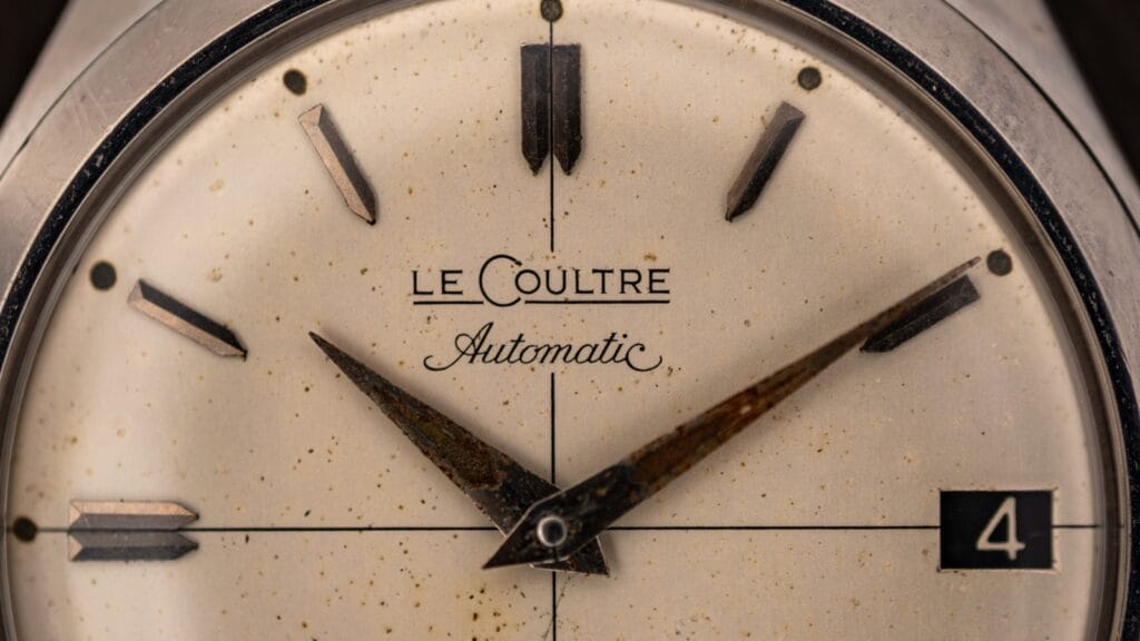 Macro of a vintage LeCoultre Automatic dial signature, aged cream dial with applied markers and a date window at four o'clock