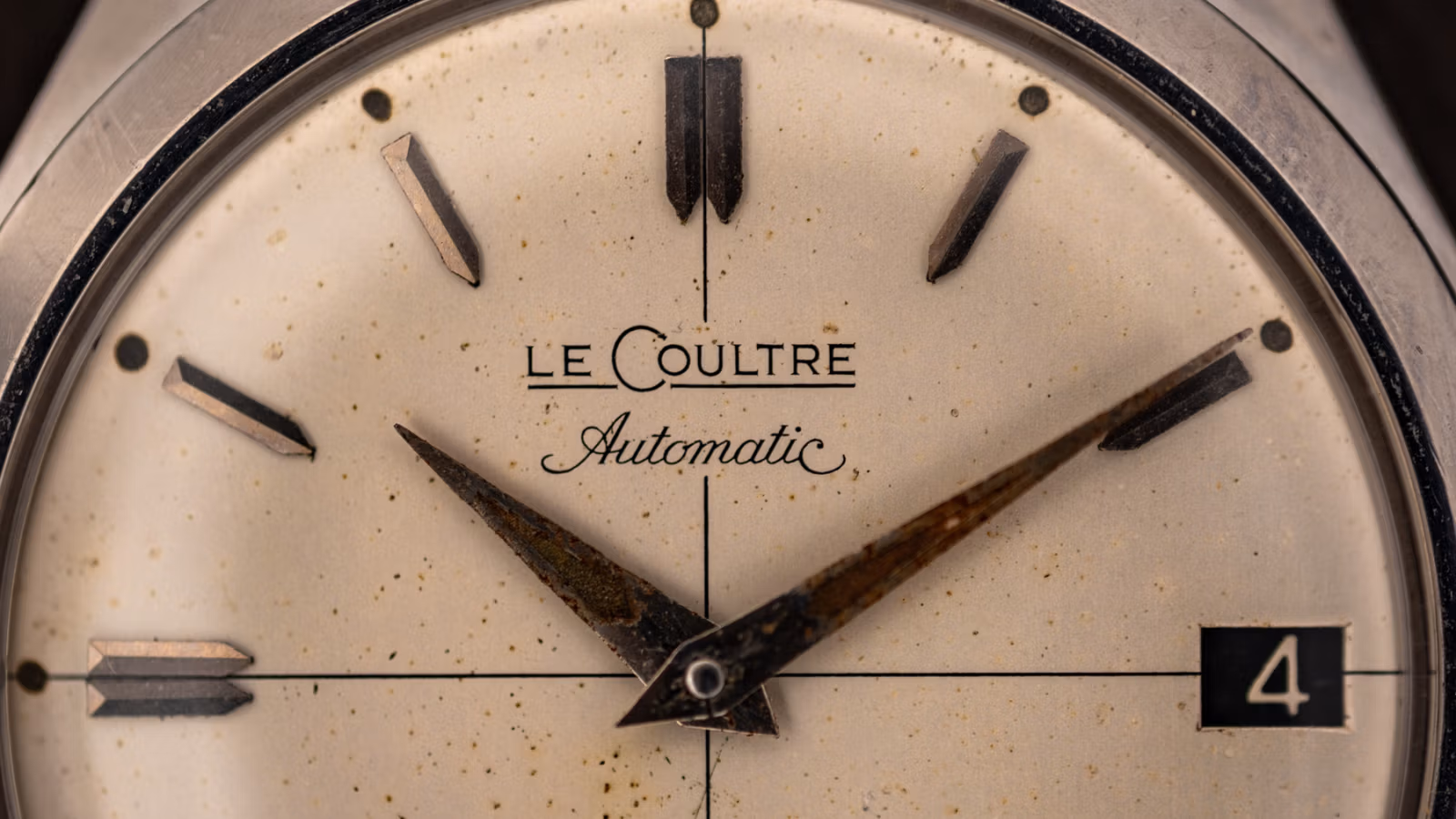 Macro of a vintage LeCoultre Automatic dial signature, aged cream dial with applied markers and a date window at four o'clock