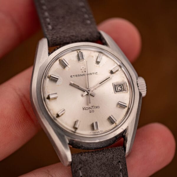 Eterna-Matic KonTiki 20 held in hand showing silver dial, applied markers and date window at three