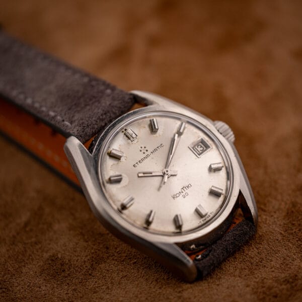Eterna KonTiki 20 automatic silver dial angled view with date at three on grey Italian suede strap