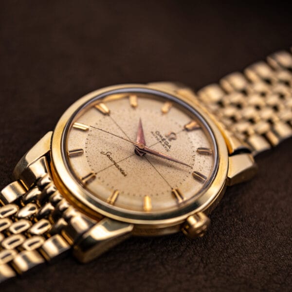 Omega Seamaster 2848 automatic angled on gold beads-of-rice bracelet showing rose-copper dauphine hands