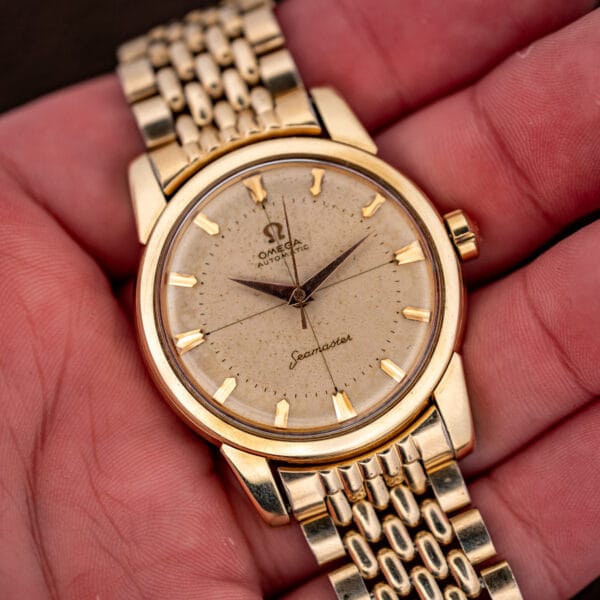 Vintage Omega Seamaster 2848 held in hand showing gold-capped case and freckled cream cross-hair dial