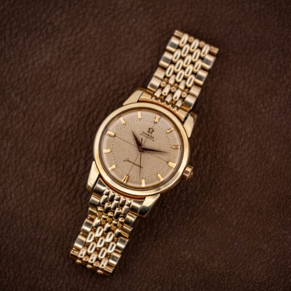 Omega Seamaster 2848 gold-capped automatic top-down on brown leather with beads-of-rice bracelet