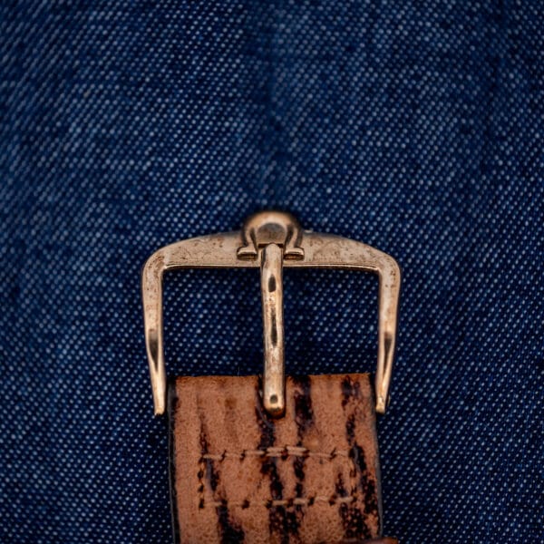Omega-signed gold-tone pin buckle and tang on the brown sharkskin strap of the Seamaster 145.029
