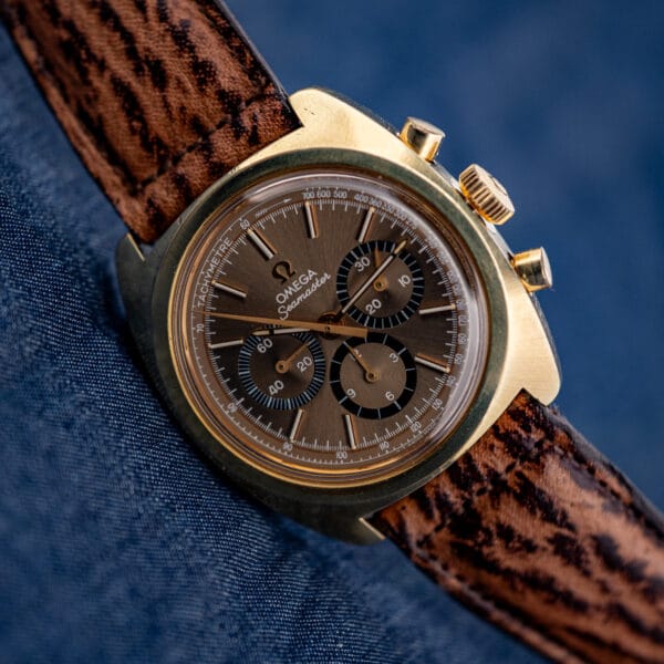 Omega Seamaster 145.029 chronograph held to the light, warm mocha dial glowing over the gold-plated Bluto case