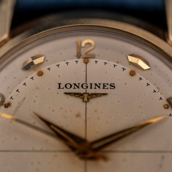 Longines winged hourglass logo and applied 12 numeral macro, crosshair line running down an aged silvered dial
