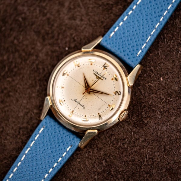 Longines Ref. 2269-1 at an angle, 10k gold filled case with faceted flared lugs and blue leather strap