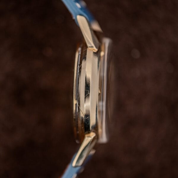 Side profile of the Longines gold filled case, faceted lugs sweeping down beneath a tall domed crystal