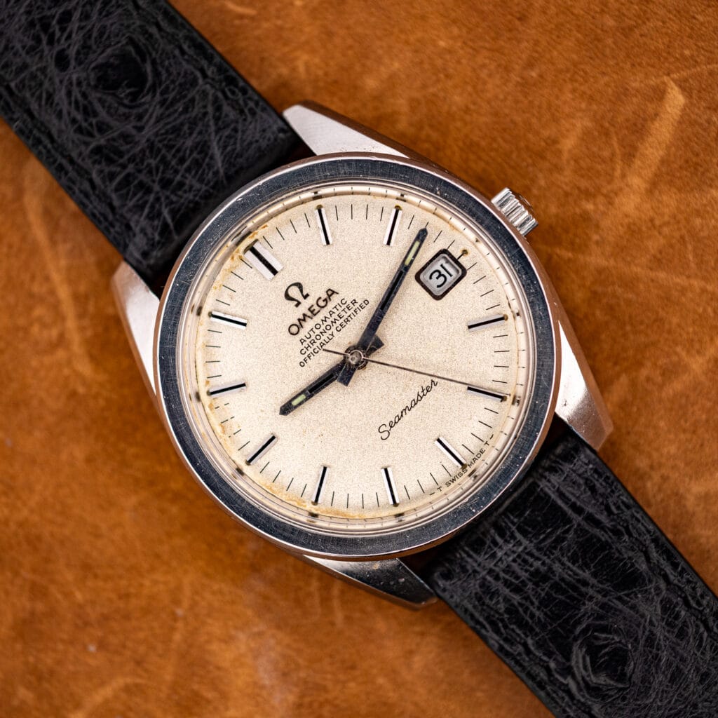Omega Seamaster 168.022 chronometer with sandblasted silver dial, black onyx-inlaid baton markers and date at three, on a black ostrich strap.