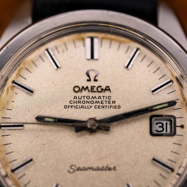 Macro of the Omega Seamaster 168.022 dial showing the Officially Certified Chronometer text under the Omega logo and light foxing across the grained silver surface.