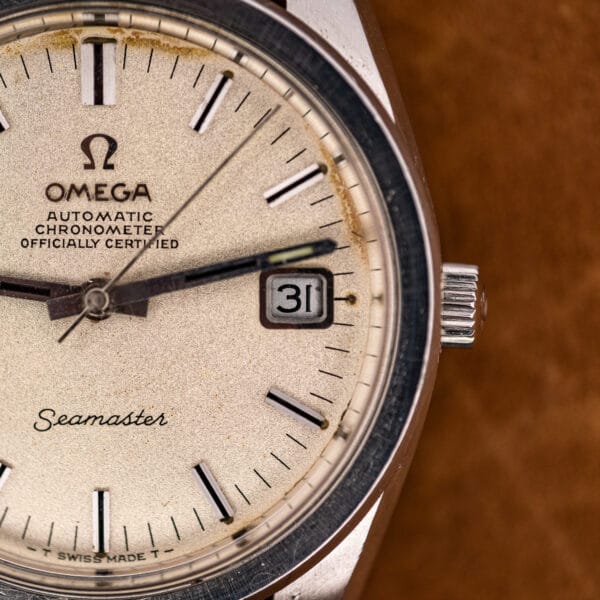 Angled macro of the Omega Seamaster 168.022 dial and signed crown, catching light across the sandblasted texture.