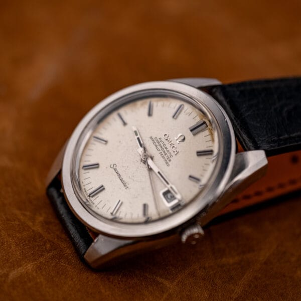Angled beauty shot of the Omega Seamaster 168.022 on ostrich leather, foxing gathered in the upper dial arc.