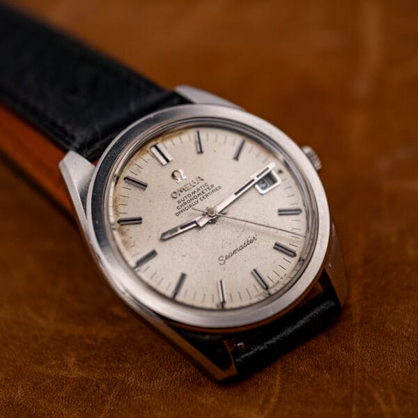 Omega Seamaster 168.022 tilted to show dial depth and the applied baton markers against the sandblasted ground.