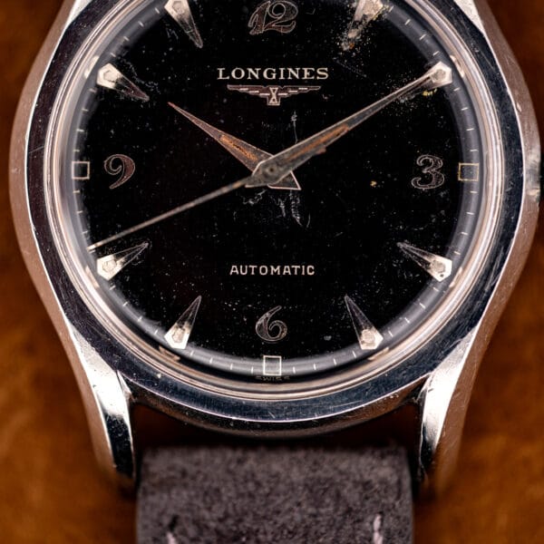 Longines 19AS black dial close-up with AUTOMATIC and SWISS printing, faceted arrow markers and honest patina