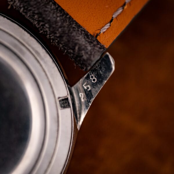 Longines 6536-1 lug flank stamped case number 258 beside anthracite suede strap with tan lining