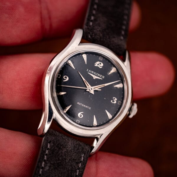 Longines 6536-1 automatic held in hand for scale, 35mm bombe case with black dial and winged logo