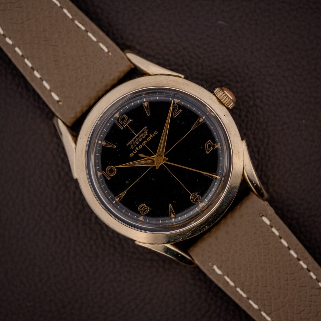 Vintage Tissot bumper automatic black gilt cross-hair dial with gold Arabic numerals on a mud grey leather strap