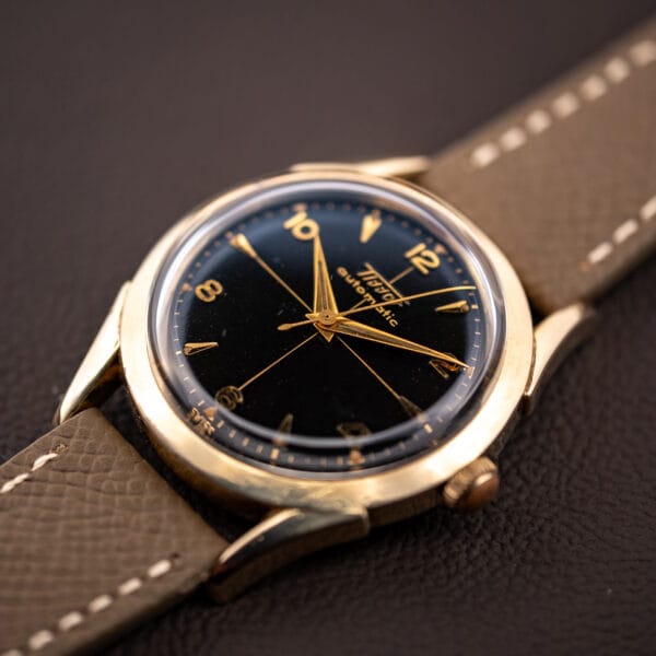 Tissot black gilt cross-hair dial close-up showing the gilt Tissot Automatic script and gold arrowhead markers