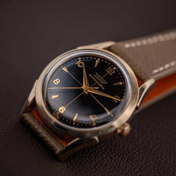 Tissot Automatic black gilt dial viewed from the crown side, gold hands over the gilt cross-hair