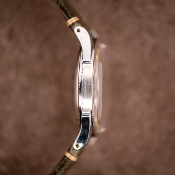Side view of Omega 2421/4 stainless case, domed acrylic crystal and tapered lugs on olive strap