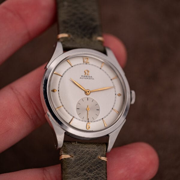 Omega 2421/4 dial in hand, gold lozenge markers at three and nine among tapered wedge batons