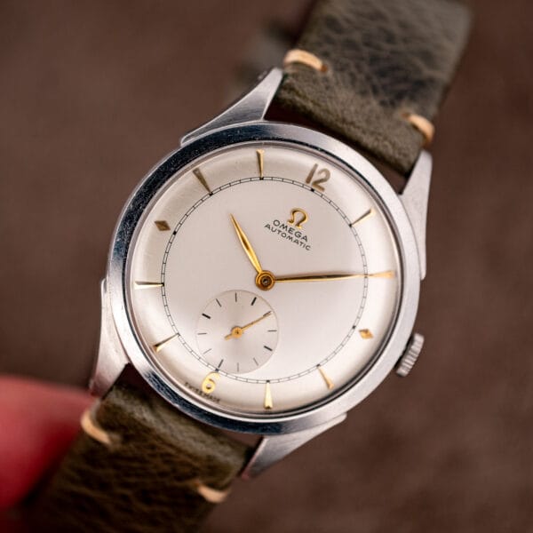 Vintage Omega automatic bumper 2421/4 in hand on olive leather, silvered two-tone dial and steel case