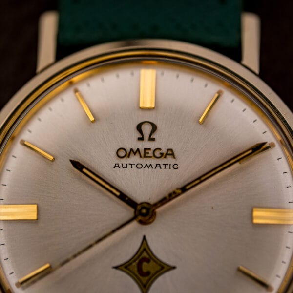 Omega Automatic dial macro showing applied Omega logo over AUTOMATIC and faceted gold baton hour markers