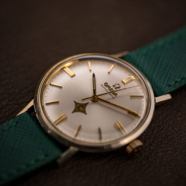 Angled view of vintage Omega Automatic 14765, silver sunburst no-date dial, 14k gold bezel and lugs
