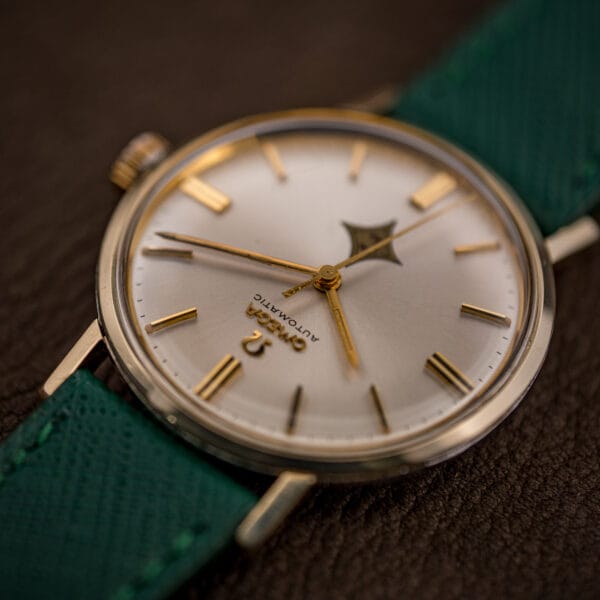 Profile of Omega 14765 showing domed acrylic crystal and 14k gold bezel over a stainless steel case