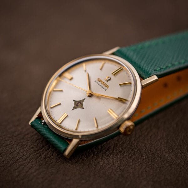Low-angle Omega Automatic dial and gold bezel, applied batons and red-C emblem catching the light