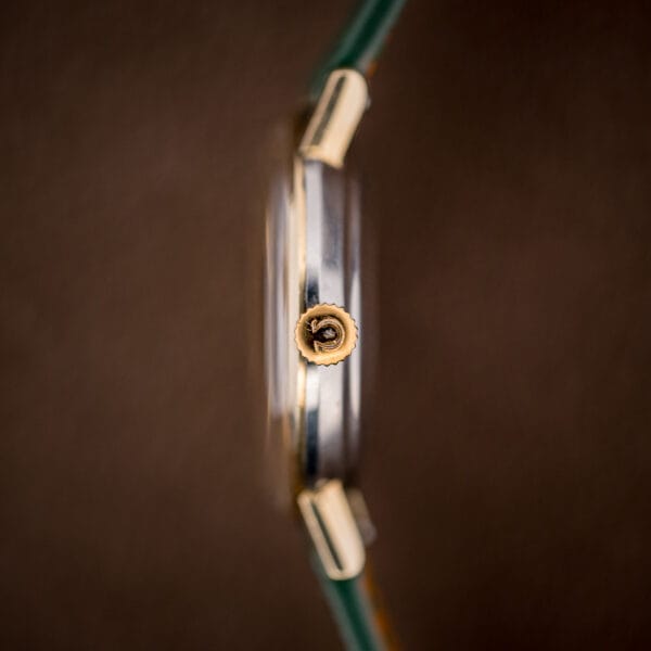 Omega signed gold crown on ref. 14765 beside the stainless steel case flank and 14k gold bezel edge