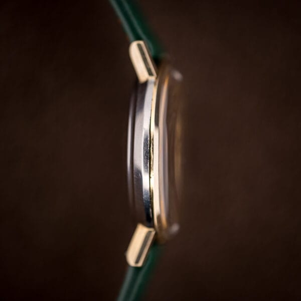 Side profile of Omega 14765 showing 14k gold bezel, stainless steel mid-case and back, gold lug tips