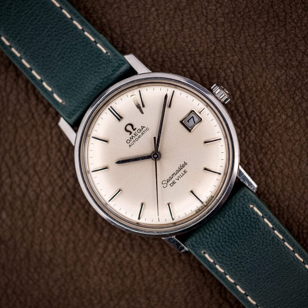Omega Seamaster De Ville 166.020 with silver sunburst dial, applied baton markers, and framed date window at three.