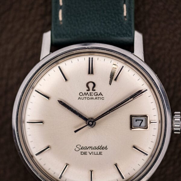 Silver dial of the Omega Seamaster De Ville 166.020 showing the applied Omega logo and Automatic designation.