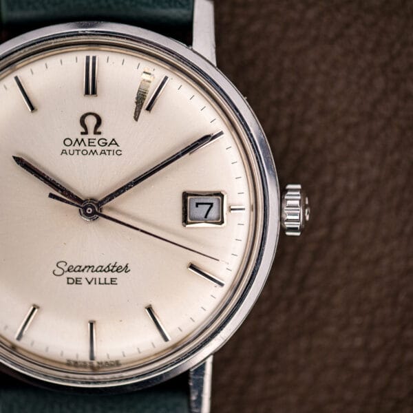 Angled view of the Omega Seamaster De Ville silver dial with faceted baton hour markers catching the light.