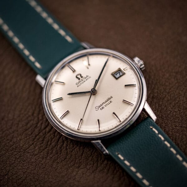 Three-quarter view of the stainless steel Omega Seamaster De Ville 166.020 case and domed acrylic crystal.